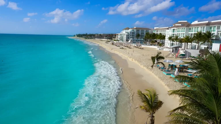 Turquoise sea and white-sand beach lined with hotels and palm trees in Playa del Carmen